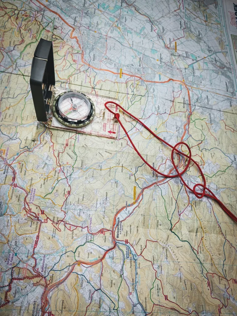 Eine detaillierte Wanderkarte mit einem Kompass und einer roten Schnur darauf, die für Orientierung und Navigation genutzt wird.